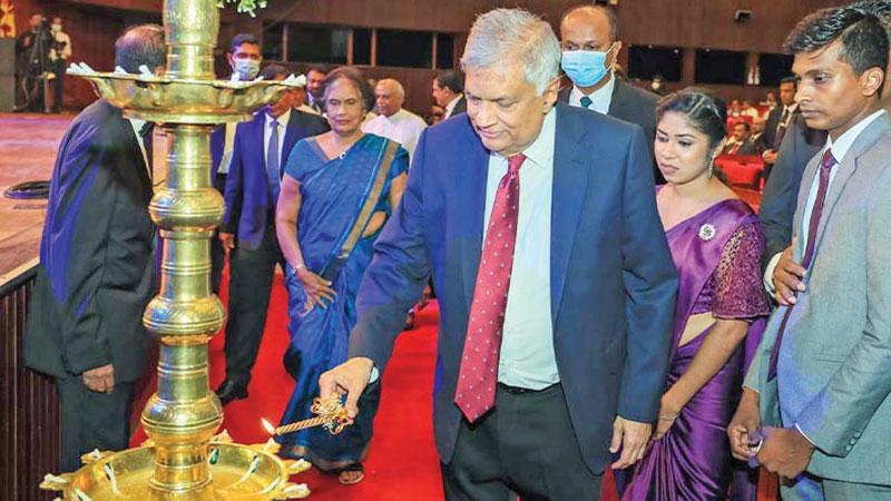 President Ranil Wickremesinghe lights the oil lamp at the event to mark the 50th anniversary of the BMICH. Former President Chandrika Bandaranaike Kumaratunga and officials look on.   Pic: Courtesy PMD