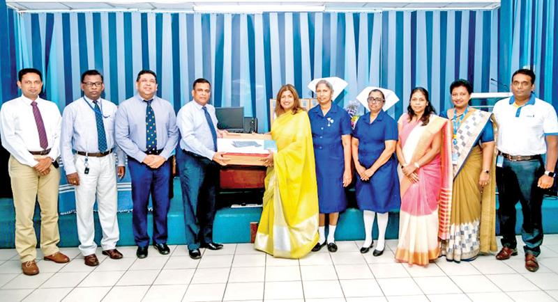 HNB Chairperson Aruni Goonetilleke presente the VDI mini computers to NHSL Deputy Director General Health Services, Dr. Kumara Wickramasinghe. NHSL medical professionals and HNB officials look on.