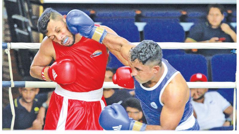 Police’s R Paventhiran (blue) lands a punch on Uphill BC’s HMNS Kaluhendiwala who won their BASL Novices Boxing meet Light Middle Weight final at the Royal MAS Arena on Friday. (Pictures by Dushmantha Mayadunne)