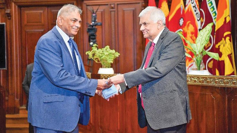 President Ranil Wickremesinghe presents the award to SLT Group Chairman Rohan Fernando.