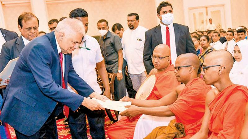 President Ranil Wickremesinghe presenting the letter of appointment to a monk teacher at the Temple Trees yesterday.