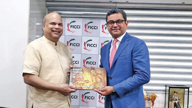 High Commissioner Milinda Moragoda presents a copy of the ‘Buddist Heritage in Sri Lanka’ to  FICCI President  Subhrakant Panda.