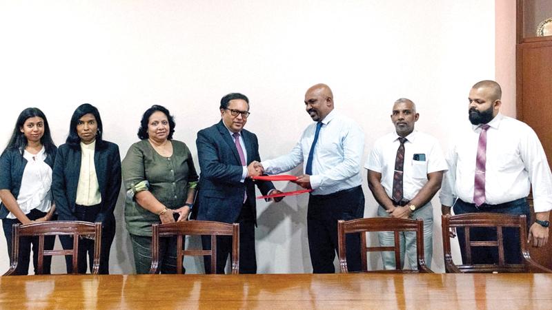 Secretary-General and CEO of the Ceylon Chamber,   Buwanekabahu Perera and Managing Director of MMA, Shanil Perera exchange copies of the MoU. Officials of both parties look on.