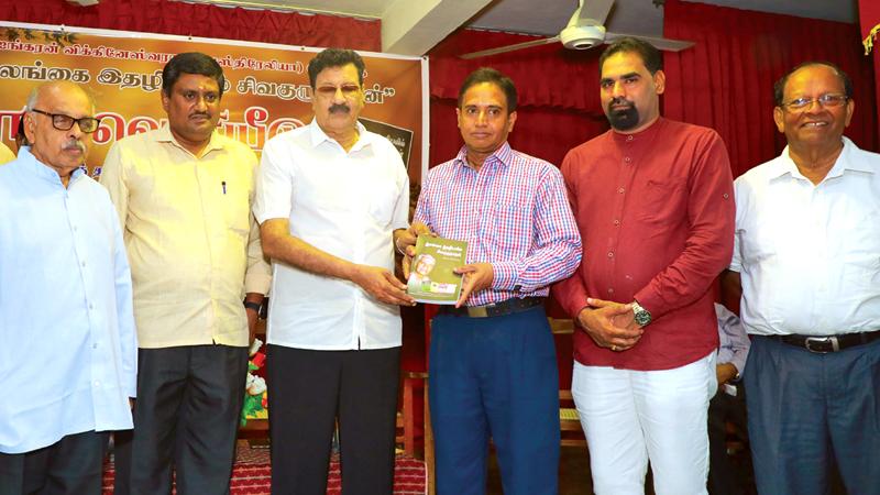 SLBC  Advisor Hassim Omar receiving maiden copy of the book from  Chief Guest ANCL Director Editorial Sisira Paranatantrie.