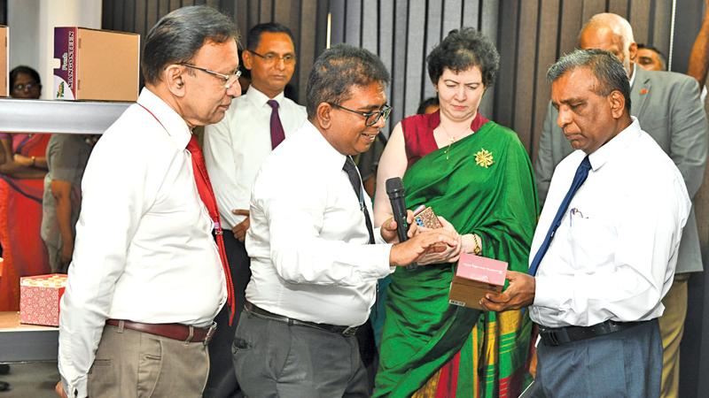 Invitees examine the packaging at the NPC. EDB Chairman Dr. Kingsley Bernard looks on.