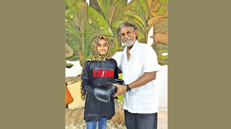 One of Sri Lanka’s promising female boxers Maryam Anas (left) of Slave Island Boxing Club receiving a pair of gloves from promoter Bandula Ratnapala